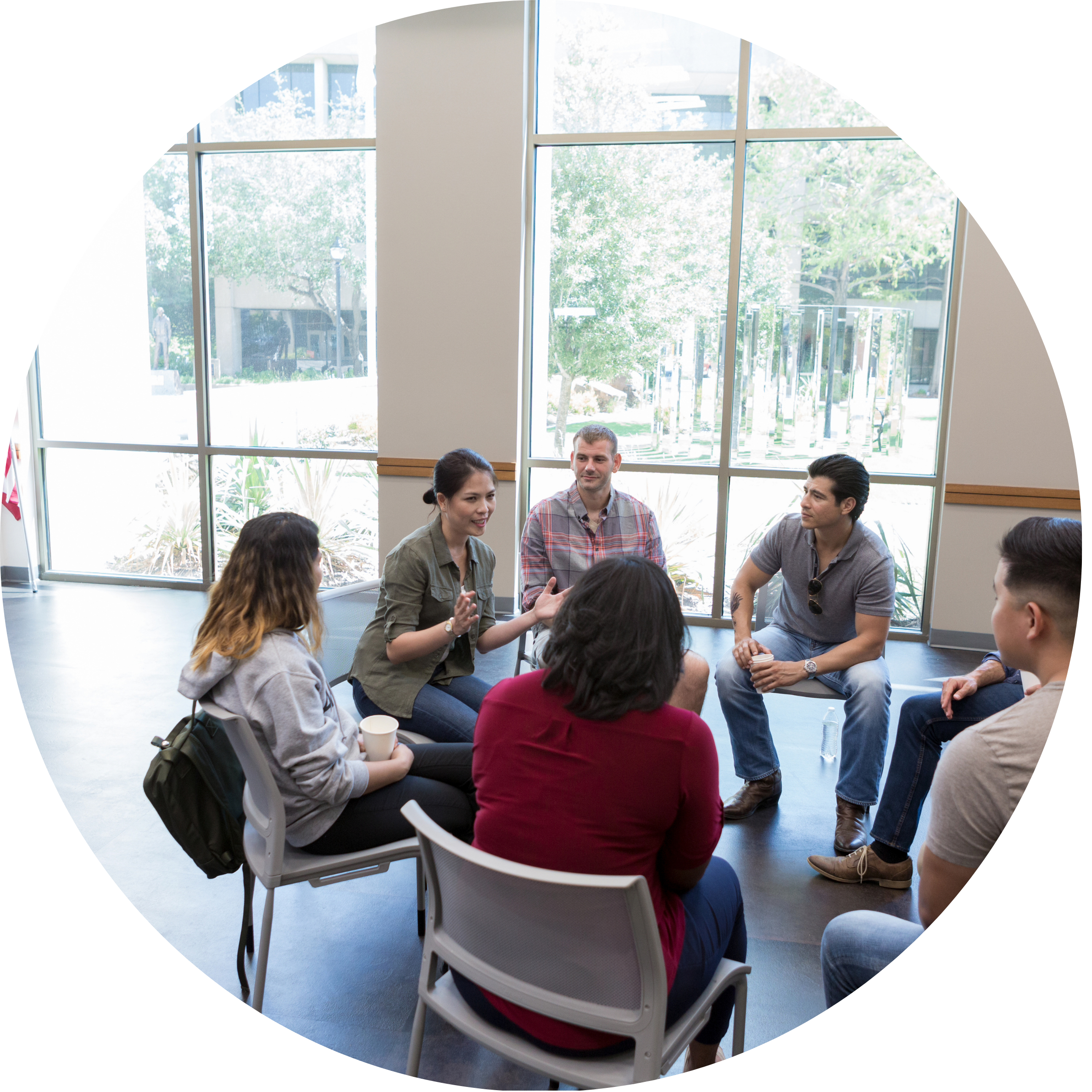 This is an image of people sitting in a circle of chairs, talking to each other.
